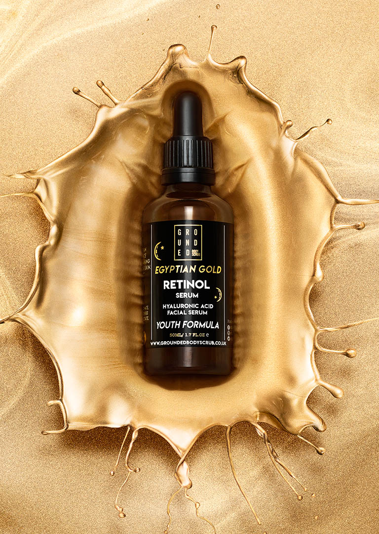 Cosmetics Photography of Grounded serum bottle in gold splash by Packshot Factory