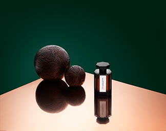 Coloured background Explorer of L'Artisan Parfumeur ambre ball and fragrance bottle