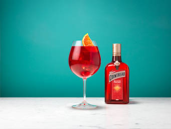 Coloured background Explorer of Cointreau Blood Orange bottle and cocktail serve